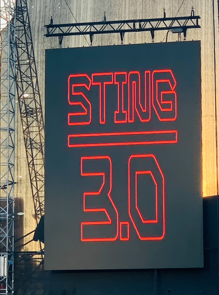 Thése, antithèse et synthèse, après  la descente en flamme du dernier Sting « Live » par Ramon Pipin ( Voir sur Gonzomusic   ) voici la réponse de Salim Zein, la live report du concert donné à Luxembourg la semaine dernière.

Par Salim ZEIN


Le 1er juillet 2025, Sting était à Luxembourg. Un concert en trio, sobre et incandescent, sous un soleil de plomb. Pour certains, c’est un chanteur qui radote ses vieux tubes. Pour d’autres, c’est un maître du temps, fidèle à lui-même, au-delà des réunions forcées et des gloires d’antan. Retour sur une soirée brûlante et sur ce que ça fait, d’aimer un artiste qui refuse de vieillir à votre place.

Le passé, parlons-en ! Certains voudraient encore ressusciter Police ( Voir sur Gonzomusic   ). Pourquoi ? Pour mieux l’enfermer dans une vitrine. Andy Summers, 80 ans, nous refait le coup du guitar hero modeste, expliquant dans une interview avec Rick Beato que les accords de "Every Breath You Take", c’était lui. "C’est moi qui l’ai fait", comme dans une vieille pub de Valérie Lemercier. Stewart Copeland ( Voir sur Gonzomusic   ), de son côté, toujours aussi brillant que bavard, s’est reconverti en storyteller officiel de l’épopée Police, alignant les documentaires, les conférences, les bouquins à dédicace.

Et Sting, pendant ce temps, avance. Lentement. Sûrement. Dignement.

Souvenir d’une messe tiède

Moi aussi, j’y ai cru. J’étais au Stade de France, ce 20 septembre 2007, quand Police s’est reformé. Soir de Grand Pardon pour les fans de la première heure. Et pourtant… Une fois passée l’émotion des premières notes de "Message in a Bottle", quelque chose s’est effondré. Le son se perdait dans le béton, la scène paraissait lointaine, glacée. Le trio récitait, appliqués mais distants, les beaux jours de Zenyatta Mondatta. Plus d’improvisation, plus de tension. Juste un beau livre d’images. À ce moment-là, j’ai compris que Sting avait eu raison de partir.

18 ans après, Luxembourg, 38°C, 12 000 cœurs
Et voilà qu’il revient, cette fois à Luxembourg. Pas de reformation, pas de feu d’artifice. Juste un concert. Sobre. En trio. Avec Dominic Miller — son complice depuis plus de 30 ans — et un heureux citoyen du royaume, batteur, à l’écoute. Pas de démonstration. Pas d’égo. Juste la musique, offerte avec une maîtrise intacte, une voix chaude et un corps encore habité. Et ce public… 12 000 personnes. Sous un cagnard de 38°C. Les femmes (et pas que) littéralement attirées par la scène comme des aimants. Il faut le voir pour le croire. Ce n’est pas de l’hystérie. C’est de l’attachement. Un lien. Une fidélité.

L’élégance du dernier des géants

Car Sting n’a plus rien à prouver. Et il le sait. Il aurait pu faire comme tant d’autres : rejouer les vieilles formules, se contenter du clin d’œil complice aux boomers. Il a préféré continuer. Écrire. Chercher. Réarranger. Explorer. Aujourd’hui, à part Springsteen, qui d’autre peut encore prétendre au titre de « dernier géant » sans tomber dans la caricature ? Déjà dans les années 80, Sinatra lui avait signé un autographe : "To the new blue eyes." Il ne s’était pas trompé. Sting, c’est l’élégance. Le crooner du chantier marin. Le gentleman rocker. L’homme qui continue à parler d’amour avec des mots simples et une aura magnétique. Il a dépassé le rock. Il est devenu une figure. Un miroir du temps. Et tant qu’il en aura envie, on sera là.

